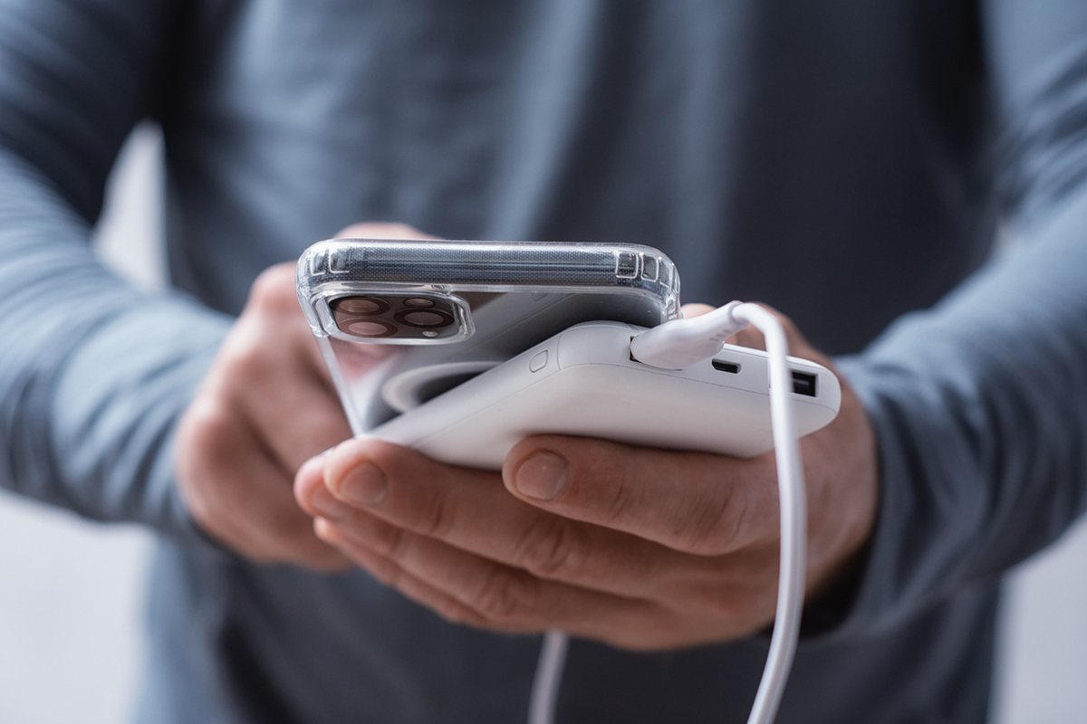 close up of a man holding a power bank and charging a smartphone. portable charger for phone and gadgets.
